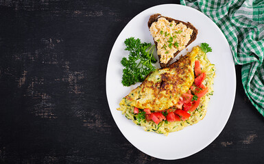 Breakfast. Omelette with zucchini, cheese and tomatoes salad with sandwich on white plate.  Frittata - italian omelet. Top view, flat lay