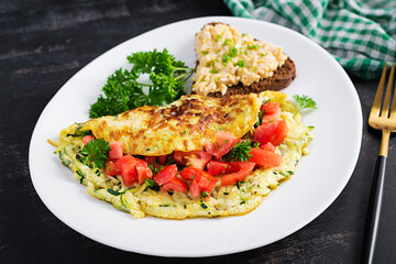 Breakfast. Omelette with zucchini, cheese and tomatoes salad with sandwich on white plate.  Frittata - italian omelet.