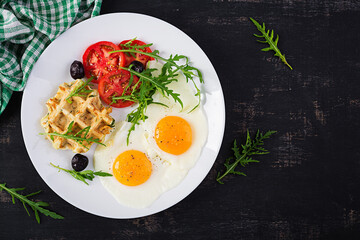 Breakfast with zucchini waffles, fried eggs, tomato, black olives and arugula on white background. Appetizers, snack, brunch. Healthy vegetarian food. Top view, overhead, copy space
