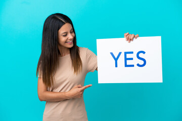 Young woman over isolated background holding a placard with text YES and  pointing it