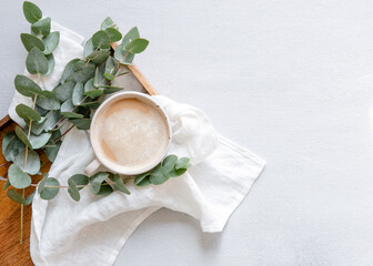 Workspace with leaves eucalyptus, cup of coffee on white background. Art frame. Flat lay, overhead view, home workspace