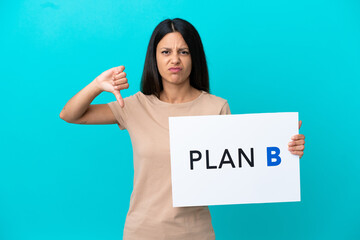 Young woman over isolated background holding a placard with the message PLAN B and doing bad signal