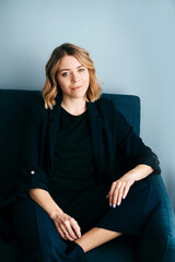Fototapeta premium Portrait of charming woman in stylish wear sitting on couch