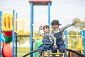 Cute little girls siblings having fun on playground outdoors on a sunny summer day. active sport...