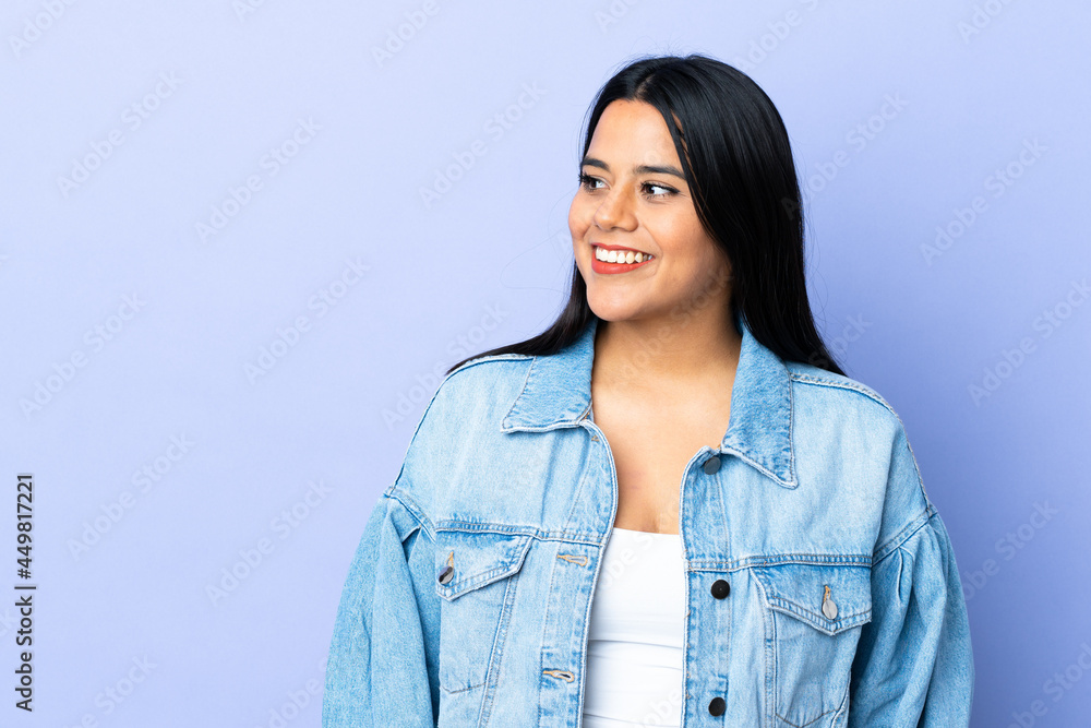 Wall mural Young latin woman woman over isolated background looking to the side and smiling