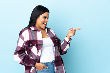 Young latin woman woman isolated on blue background pointing finger to the side and presenting a product