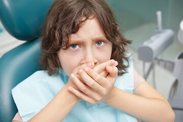 Close up of a scared little boy refusing opening his mouth for dental treatment