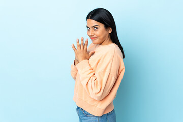 Young latin woman woman isolated on blue background scheming something