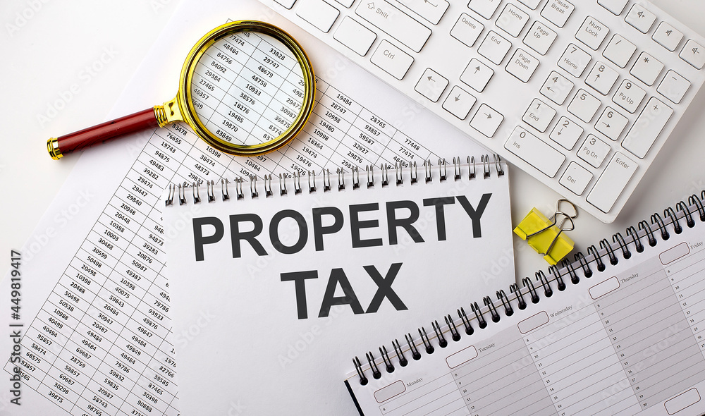 Aufkleber property tax text written on a notebook on chart with keyboard and planning