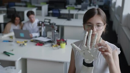 Close up view of a young lady that looks on the 3D printed hand - Powered by Adobe