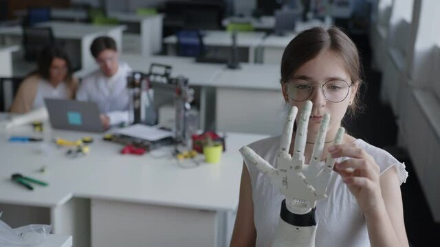 Close up view of a young lady that looks on the 3D printed hand