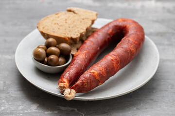 typical portuguese smoked sausage chourico with olives and bread