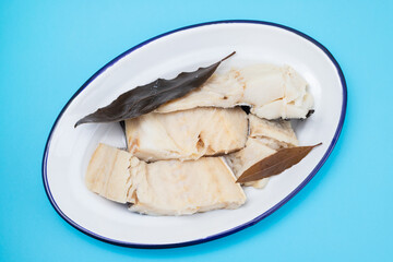 boiled cod fish with bay leaf on white dish