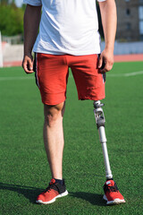 Fototapeta premium Close up of a man athlete with a prosthesis on his leg standing at the stadium on the field. Sport concept