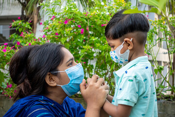 Asian mother teaches her child about the need to wear a safety mask in a green garden. Covid-19 epidemic, Lockdown, and home quarantine time safety concept. Educational and safety concept.