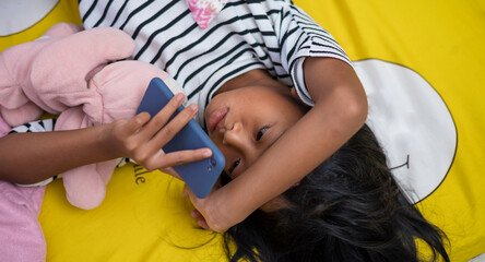 Asian girl watching content on her bed in the morning using a smartphone