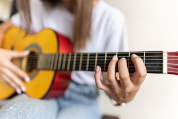 Fototapeta na wymiar Detailed picture of a female's hand practising different chords on a guitar