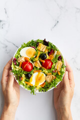 Salad with lettuce, egg, tuna, olives and honey and mustard vinaigrette on white background
