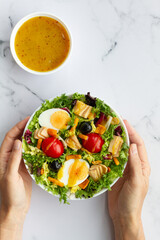 Salad with lettuce, egg, tuna, olives and honey and mustard vinaigrette on white background