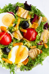 Salad with lettuce, egg, tuna, olives and honey and mustard vinaigrette on white background