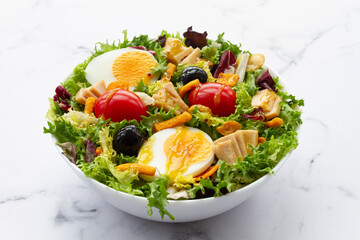 Salad with lettuce, egg, tuna, olives and honey and mustard vinaigrette on white background