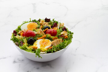 Salad with lettuce, egg, tuna, olives and honey and mustard vinaigrette on white background