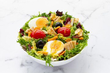 Salad with lettuce, egg, tuna, olives and honey and mustard vinaigrette on white background