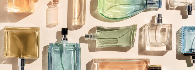 perfume bottles. a lot of transparent multicolored glass bottles of cosmetics, on a beige...