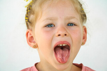 Cheerful child. Girl laughs close-up of the face on a white background. A little girl show tongue throat. portrait with wide open mouth and protruding tongue. with clear view pulls out long tongue - obrazy, fototapety, plakaty
