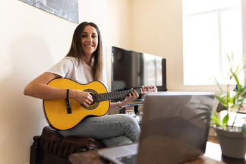 Attractive young female searching on the internet for tutorials to learn at home new chords and how...