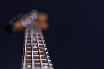 Close-up of a bass guitar fretboard on a blurred dark background.