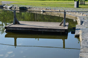 a wooden raft is tied to a taut rope. self-service ferry across the river, pond. People get on and pull their hands to the other bank by their own strength. Floating pier on the lake.