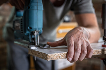 Close-up process of cutting wood board with jigsaw.