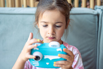 A little girl takes a photo on a camera for instant photo printing.