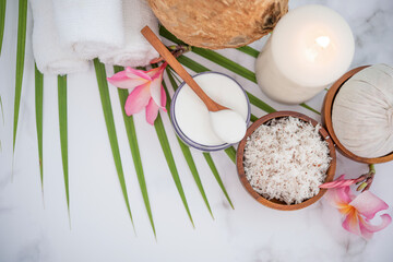 Coconut oil, tropical leaves and fresh coconuts. Spa coconut products on light wooden background. Spa still life of organic cosmetics with coconuts on a light wooden background, body care concept.