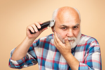 Portrait of old man being trimmed with hair clipper in barbershop, haircut with an electric razor....