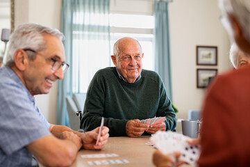 Senior joyful friends playing cards together