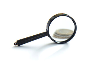 Fototapeta premium Magnifier and stack of coins isolated on white background. Concept of keeping money, investing