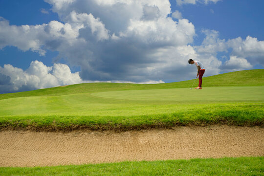 Golfers putting golf balls on the golf course in the morning.