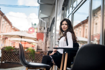 Young beautiful girl sitting in a coffee shop and waiting for her cappuccino