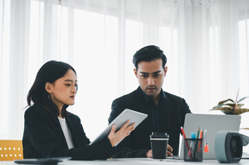 Businesswoman discussing charts and graphs showing on tablet screen with friend with smiling faces in the meeting room. Brainstorming and teamwork concept.