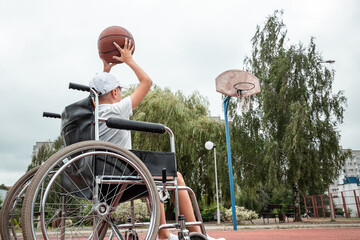 Boy in a wheelchair on the basketball court. Rehabilitation, disabled person, paralyzed, happy disabled child.