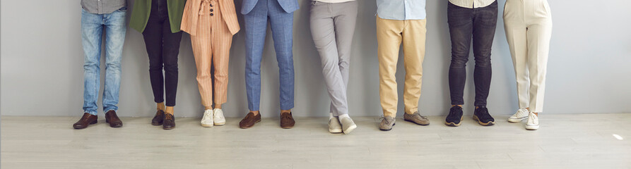 Cropped image of legs of people standing in a row near the wall waiting for an interview....