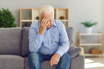 Retired old granddad sitting on couch at home, crying, grieving over loss of wife, feeling...