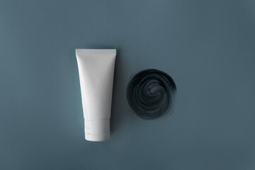 Top view above blank label facial skincare white tube bottle product smear detox clay or mud mask spin shape texture on plain grey green isolated background. Skincare reduce pore, blackheads

