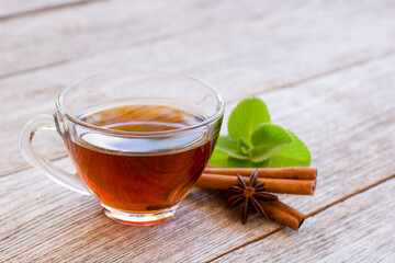 Cinnamon herbal tea in glass cup and cinnamon stick on wooden table