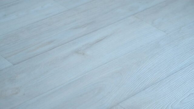 Light grey linoleum surface on floor with wooden pattern, wood texture. Looks like laminate. Modern material for renovation.