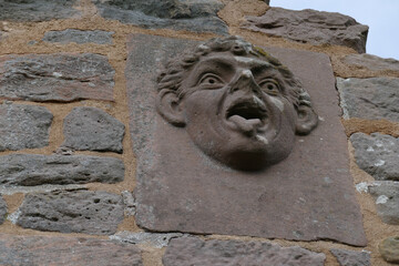 Laughing grimace carved in stone in the almost 1000 year old castle Hanstein, Germany. It...