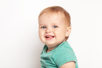 Naklejka premium Infant child baby boy in green t-shirt laughs happy looking at the camera isolated on a white background. Childcare and upbringing concept.