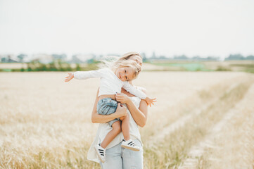 Beautiful mother and her daughter baby girl at the wheat field in sunny day in Belarus